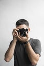 Handsome young bearded man in a black shirt holding vintage old-fashioned film camera on a white background and looking Royalty Free Stock Photo