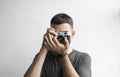 Handsome young bearded man in a black shirt holding vintage old-fashioned film camera on a white background and looking Royalty Free Stock Photo