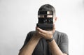 Handsome young bearded man in a black shirt holding vintage old-fashioned film camera on a white background and looking Royalty Free Stock Photo