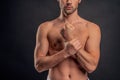 Handsome young bearded man . Cropped image of topless muscular man is standing on gray background. Close-up of man holding Royalty Free Stock Photo