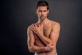 Handsome young bearded man isolated. Cropped image of shirtless muscular man is standing on gray background. Man holding his elbow Royalty Free Stock Photo