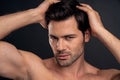 Handsome young bearded man isolated. Portrait of shirtless muscular man is standing on grey background and holding his hair Royalty Free Stock Photo