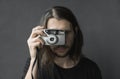 Handsome young bearded man with a long hair and in a black shirt holding vintage old-fashioned film camera on a black Royalty Free Stock Photo