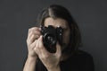 Handsome young bearded man with a long hair and in a black shirt holding vintage old-fashioned film camera on a black Royalty Free Stock Photo