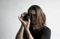 Handsome young bearded man with a long hair and in a black shirt holding vintage old-fashioned film camera on a white Royalty Free Stock Photo