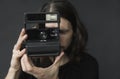 Handsome young bearded man with a long hair and in a black shirt holding vintage old-fashioned film camera on a black Royalty Free Stock Photo