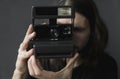 Handsome young bearded man with a long hair and in a black shirt holding vintage old-fashioned film camera on a black Royalty Free Stock Photo