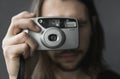 Handsome young bearded man with a long hair and in a black shirt holding vintage old-fashioned film camera on a black Royalty Free Stock Photo