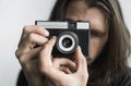Handsome young bearded man with a long hair and in a black shirt holding vintage old-fashioned film camera on a white Royalty Free Stock Photo