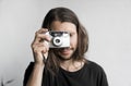 Handsome young bearded man with a long hair and in a black shirt holding vintage old-fashioned film camera on a white Royalty Free Stock Photo