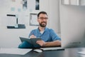 Handsome young bearded man sits in his office looking happy while working on business project looks satisfied, takes Royalty Free Stock Photo