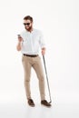 Handsome young bearded man standing over white wall with golfstick Royalty Free Stock Photo