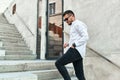 Handsome young bearded man in stylish casual outfit and black sunglasses, goes up the concrete stairs in urban city center Royalty Free Stock Photo