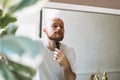 Handsome young bearded man trimming his beard with machine in bathroom at home Royalty Free Stock Photo