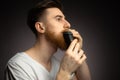 Handsome young bearded man trimming his beard with a trimmer Royalty Free Stock Photo