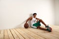 Handsome young black basketball player sitting on the wooden floor Royalty Free Stock Photo