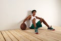 Handsome young black basketball player sitting on the wooden floor Royalty Free Stock Photo