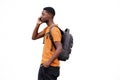 Handsome young black man with backpack walking and talking on cellphone by white wall Royalty Free Stock Photo