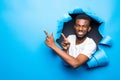 Young handsome african man pointed side throught blue paper hole Royalty Free Stock Photo