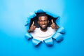 Young handsome african man with thumbs up gesture throught blue paper hole Royalty Free Stock Photo