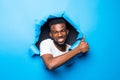 Young handsome african man with thumbs up gesture throught blue paper hole Royalty Free Stock Photo