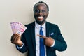 Handsome young black man wearing business suit holding mexican pesos banknotes smiling happy pointing with hand and finger Royalty Free Stock Photo