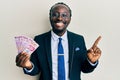 Handsome young black man wearing business suit holding mexican pesos banknotes smiling happy pointing with hand and finger to the Royalty Free Stock Photo