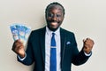Handsome young black man wearing business suit holding 100 rands banknotes screaming proud, celebrating victory and success very Royalty Free Stock Photo