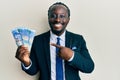 Handsome young black man wearing business suit holding 100 rands banknotes smiling happy pointing with hand and finger Royalty Free Stock Photo