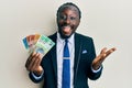 Handsome young black man wearing business suit and tie holding australian dollars celebrating achievement with happy smile and Royalty Free Stock Photo