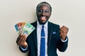 Handsome young black man wearing business suit and tie holding australian dollars screaming proud, celebrating victory and success Royalty Free Stock Photo