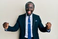 Handsome young black man wearing business suit and tie screaming proud, celebrating victory and success very excited with raised Royalty Free Stock Photo