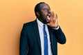 Handsome young black man wearing business suit and tie shouting and screaming loud to side with hand on mouth Royalty Free Stock Photo