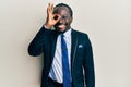 Handsome young black man wearing business suit and tie smiling happy doing ok sign with hand on eye looking through fingers Royalty Free Stock Photo