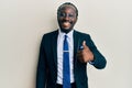 Handsome young black man wearing business suit and tie smiling happy and positive, thumb up doing excellent and approval sign Royalty Free Stock Photo