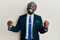 Handsome young black man wearing business suit and tie very happy and excited doing winner gesture with arms raised, smiling and Royalty Free Stock Photo