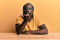 Handsome young black man wearing casual clothes sitting on the table looking at the camera blowing a kiss with hand on air being Royalty Free Stock Photo