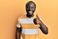 Handsome young black man wearing casual yellow tshirt smiling happy and positive, thumb up doing excellent and approval sign Royalty Free Stock Photo