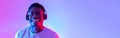 Handsome young black man wearing headphones, listening to music with closed eyes in neon light, banner design Royalty Free Stock Photo