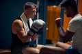 Handsome young boxing player in dressing room with coach preparing for workout