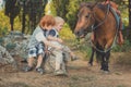 Handsome Young boy with red hair and blue eyes playing with his friend horse pony in forest.Huge love between kid shild and animal