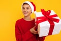 Handsome young boy in a red sweatshirt with a gift and a santa claus hat. received a christmas present. emotions of joy Royalty Free Stock Photo