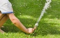 Handsome young boy watering garden with rubber hosepipe. green lawn Royalty Free Stock Photo