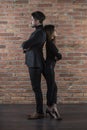 Handsome young business couple standing back to back in front of a brick wall Royalty Free Stock Photo