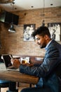 Handsome young business man, blogger or remote working with laptop in bar Royalty Free Stock Photo