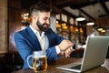 Handsome young business man, blogger or remote working with laptop in bar Royalty Free Stock Photo