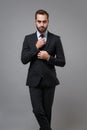 Handsome young business man in classic black suit shirt tie posing isolated on grey wall background studio portrait Royalty Free Stock Photo