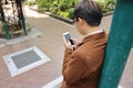 Handsome young business man looking mobile phone in his hand while leaning a pole at outdoor. Royalty Free Stock Photo