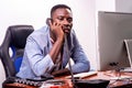 Young business man working in office with laptop and talking on mobile phone Royalty Free Stock Photo