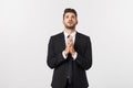 Handsome young business man standing praying, isolated over white background. Concept of idea, ask question, think up Royalty Free Stock Photo